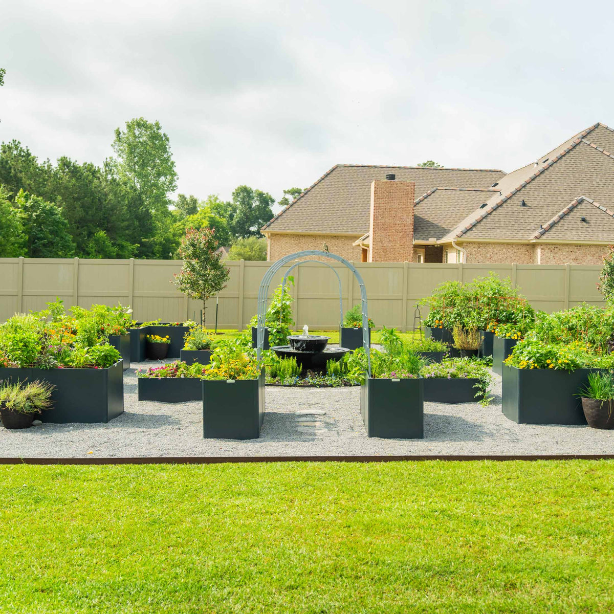 A back garden laid out with several metal raised beds, an arch trellis and planted borders